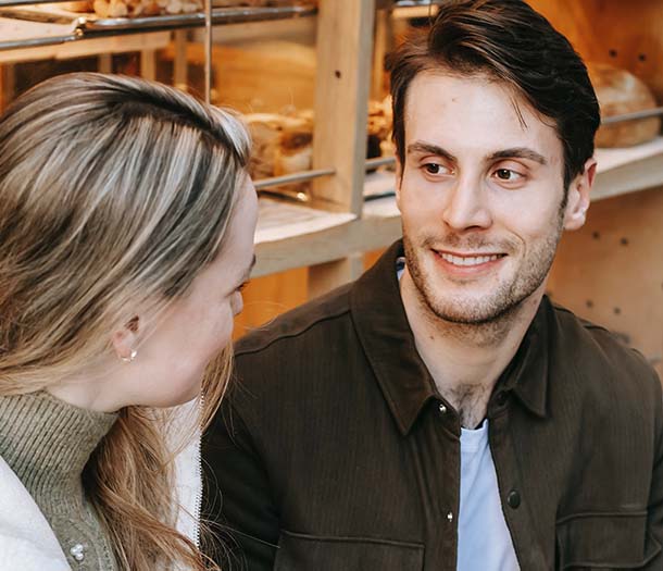 happy young couple chatting with takeaway coffee and holding hands