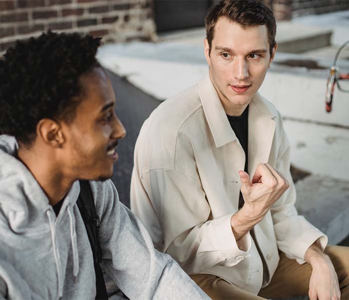 happy young diverse guys talking on city street