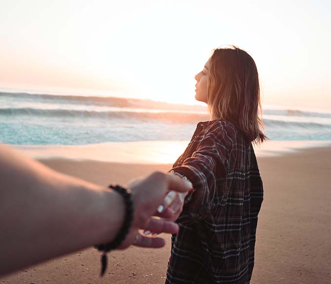 woman holding hands with person facing ocean