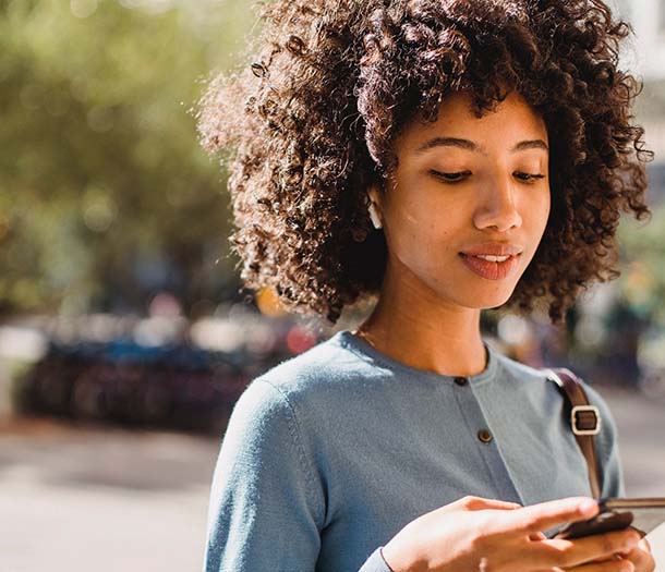 woman with curly hair holding a cellphone