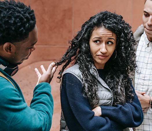 young diverse guys touching hair of upset ethnic female student